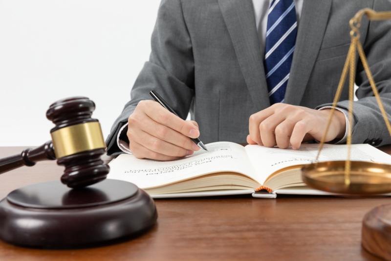 persona escribiendo y al lado un mayete de justicia